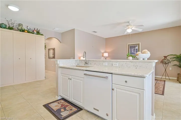 Kitchen featuring white cabinetry, light tile patterned floors, dishwasher, ceiling fan, and sink