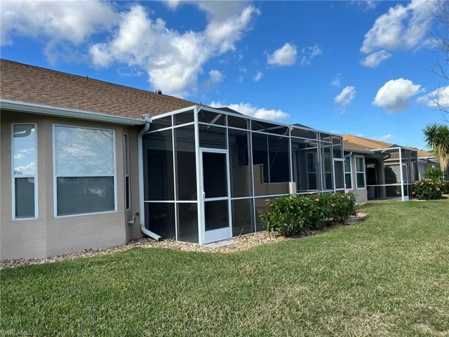 Rear view of property with a yard and glass enclosure