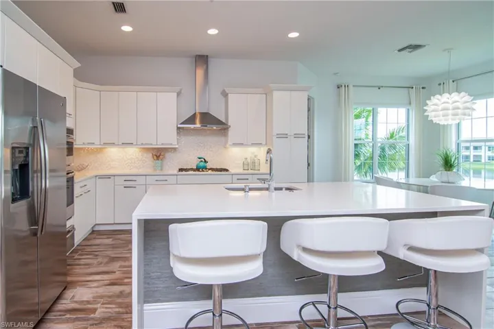 Stainless GE appliances, exhaust hood, snow white quartz countertops with waterfall island.