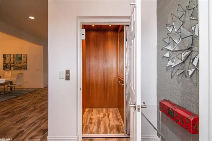 Private elevator with upgraded cherrywood paneling, mirror and matching wood plank tile floor.