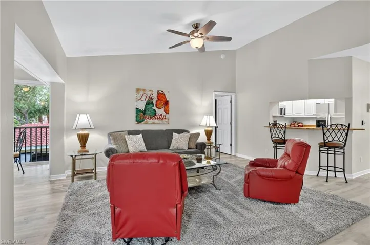 Living room with light wood-type flooring, ceiling fan, and high vaulted ceiling