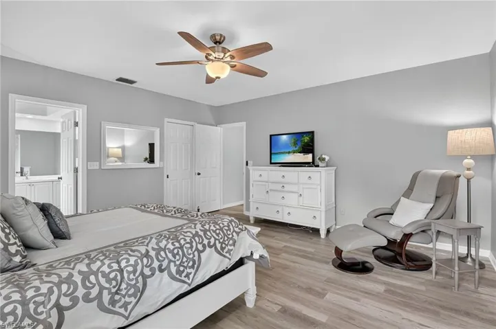 Bedroom featuring light wood-style floors, connected bathroom, a ceiling fan, and a closet