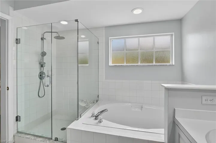 Bathroom featuring a garden tub, a shower stall, and vanity