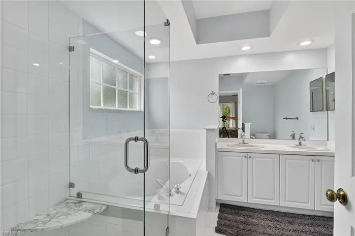 Bathroom featuring a bath, a stall shower, double vanity, and recessed lighting