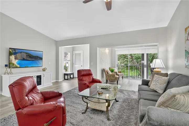 Living area with light wood-style floors, ceiling fan, and lofted ceiling