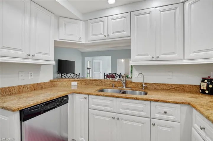 Kitchen featuring dishwasher, white cabinets, light stone counters, and recessed lighting