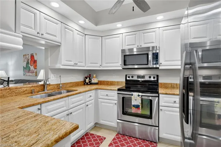 Kitchen with appliances with stainless steel finishes, recessed lighting, white cabinetry, light tile patterned floors, and a ceiling fan
