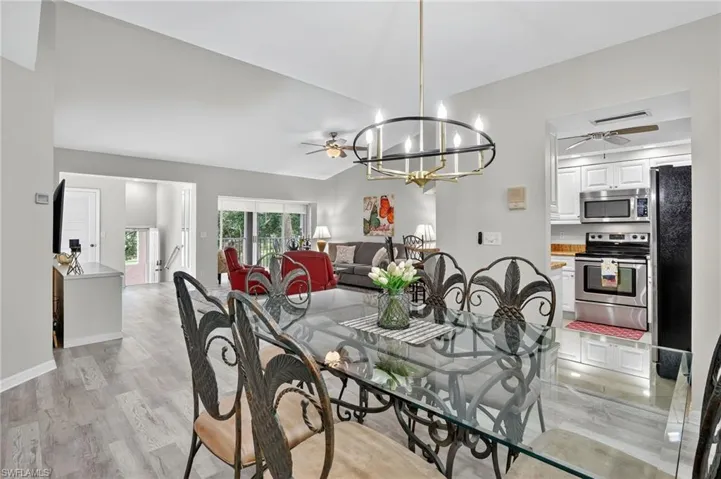 Dining area featuring a ceiling fan, light wood finished floors, a chandelier, and vaulted ceiling