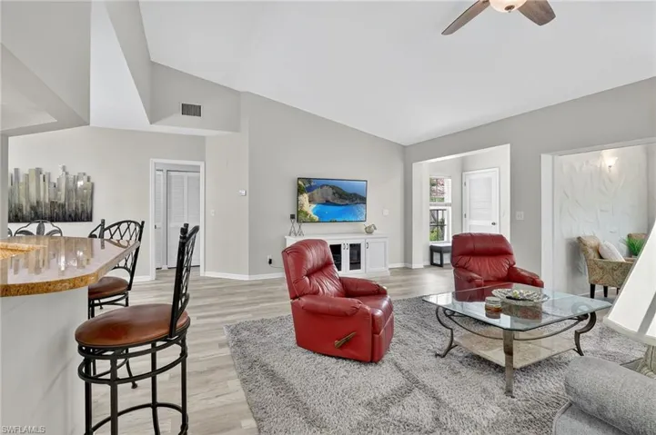 Living room featuring light wood finished floors, a ceiling fan, and high vaulted ceiling