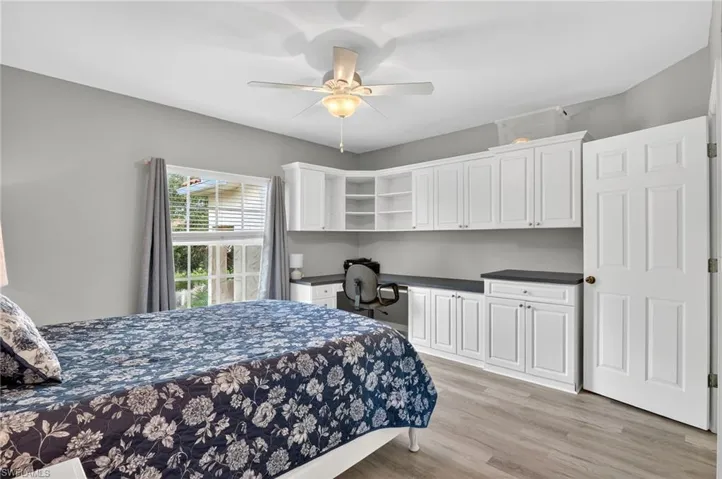 Bedroom featuring built in desk, light wood-type flooring, and ceiling fan