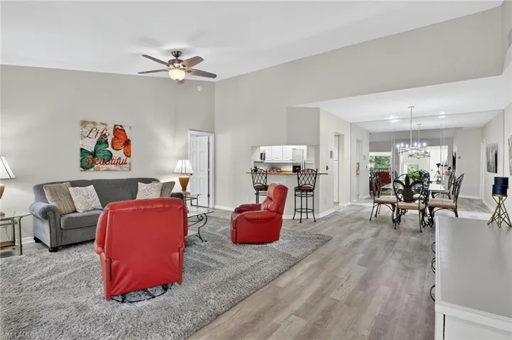 Living area featuring light wood-style floors, ceiling fan, and a chandelier