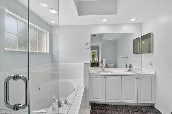 Full bathroom with plenty of natural light, a garden tub, recessed lighting, double vanity, and a shower with shower door