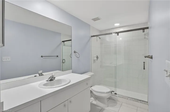 Full bath with vanity, a stall shower, and tile patterned flooring