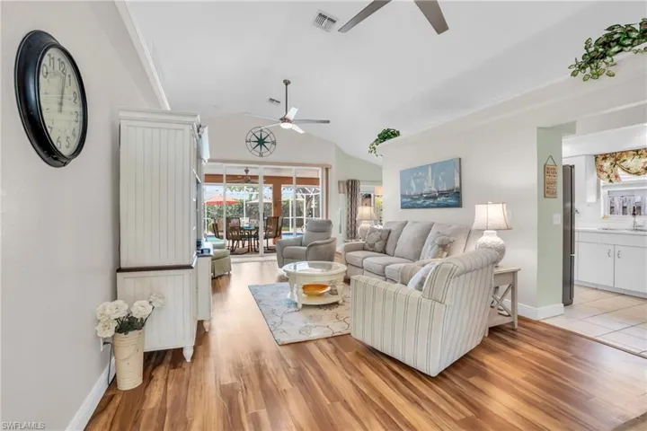 Living room featuring sink, light wood-type flooring, ceiling fan, and lofted ceiling