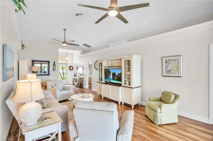 Living room featuring lofted ceiling, ceiling fan, and light wood-type flooring
