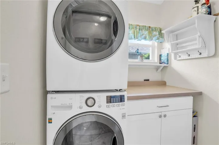 Laundry area with stacked washer and dryer and cabinets