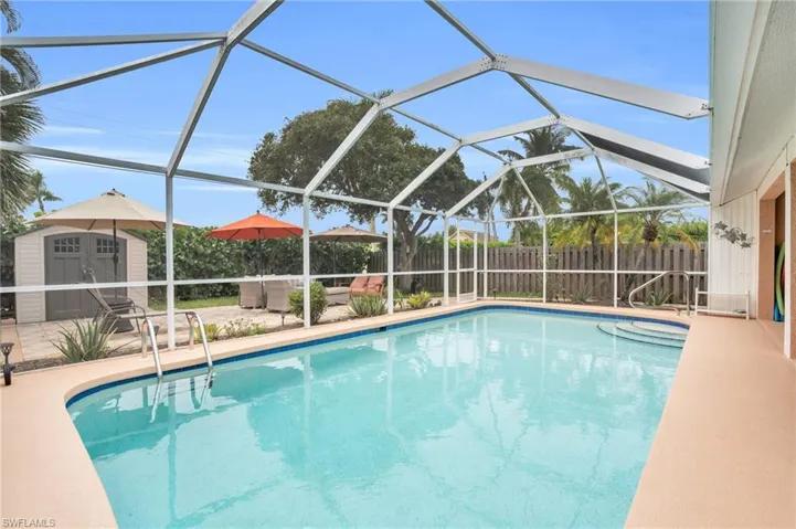 View of swimming pool with a storage unit, glass enclosure, and a patio area
