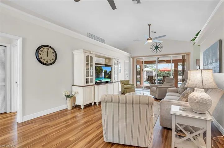 Living room featuring light wood-type flooring, ceiling fan, and lofted ceiling