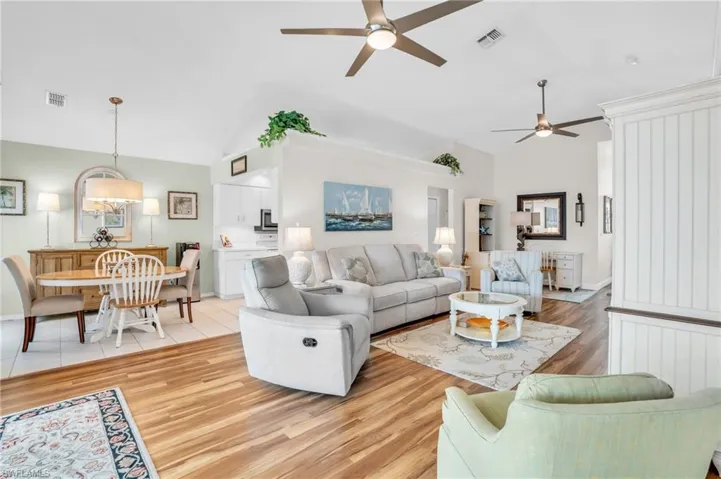 Living room with ceiling fan, light hardwood / wood-style flooring, and lofted ceiling