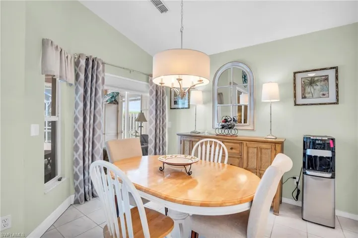 Tiled dining space with lofted ceiling and a notable chandelier