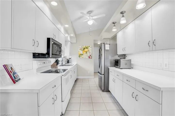 Kitchen featuring ceiling fan, tasteful backsplash, vaulted ceiling, and stainless steel appliances