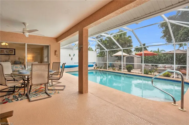 View of swimming pool featuring a patio, glass enclosure, a storage unit, and ceiling fan
