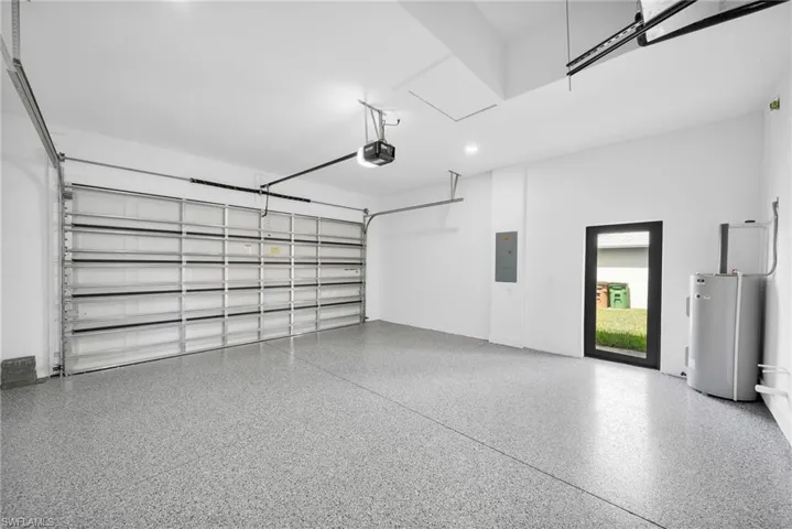 Garage with electric water heater, electric panel, and a garage door opener