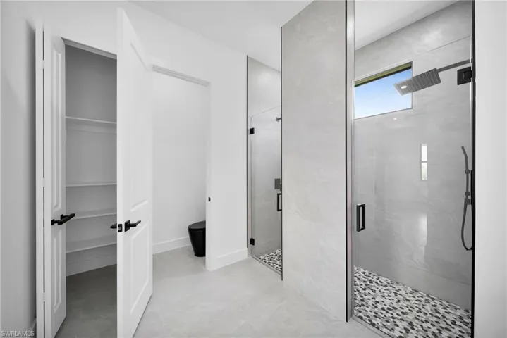 Bathroom with a shower with door and tile patterned flooring