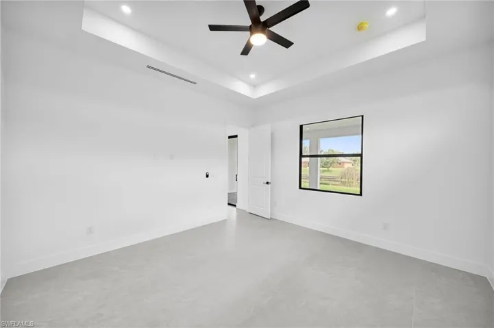 Tiled spare room featuring ceiling fan and a raised ceiling