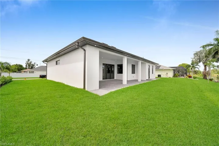 Rear view of house with a patio area and a lawn