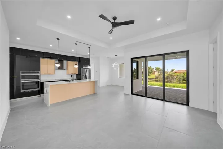 Kitchen featuring light tile patterned flooring, ceiling fan, a tray ceiling, and stainless steel appliances