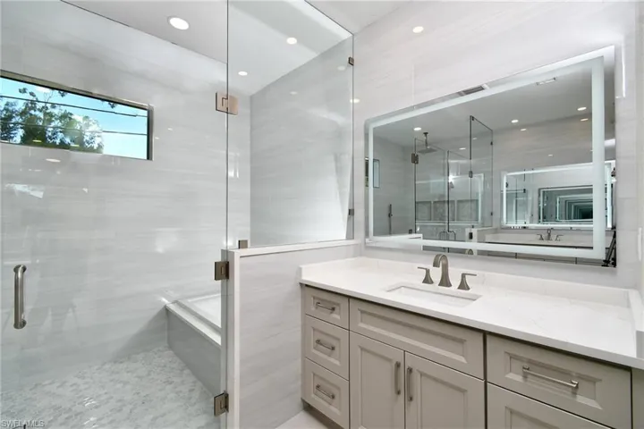 Bathroom featuring vanity, a shower stall, recessed lighting, and tile walls