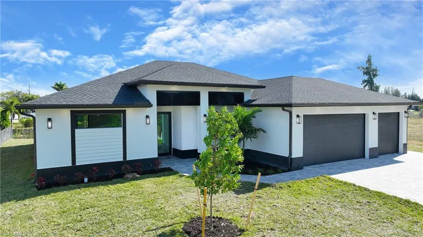 View of front of house featuring an attached garage, decorative driveway, roof with shingles, and a front lawn