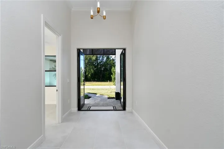 Foyer with a chandelier, ornamental molding, and tile patterned flooring