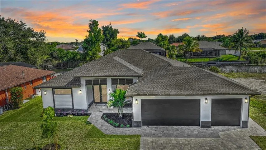 View of front of home featuring roof with shingles, stucco siding, decorative driveway, a front yard, and an attached garage