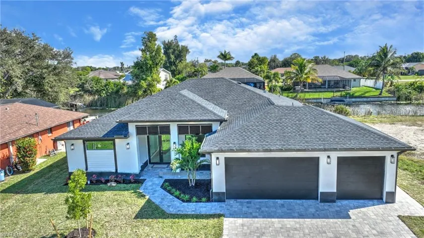 View of front of house with roof with shingles, a front yard, decorative driveway, a garage, and stucco siding