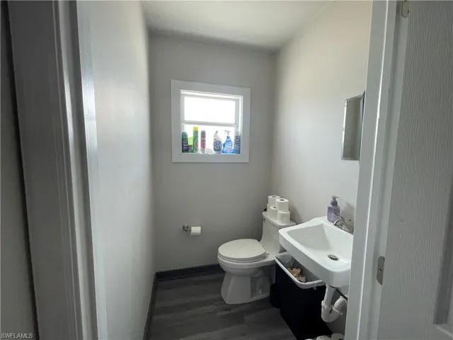 Half bathroom featuring toilet and dark wood-style flooring