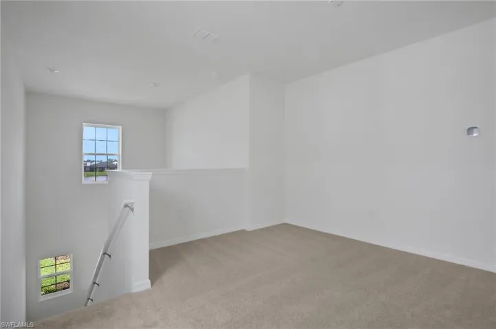 Empty room featuring light colored carpet and baseboards