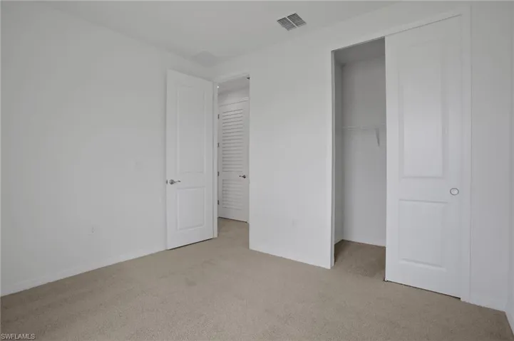 Unfurnished bedroom featuring light carpet and a closet