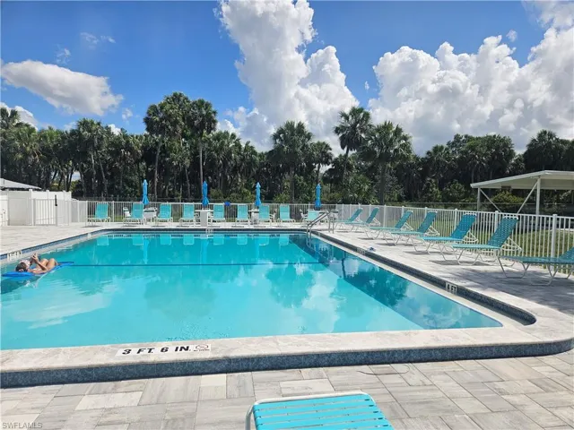 Community pool with a patio area and view of wooded area