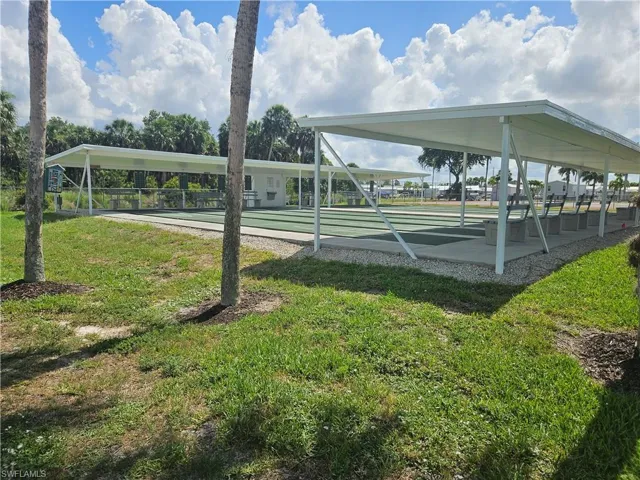 View of property's community with a yard and shuffleboard