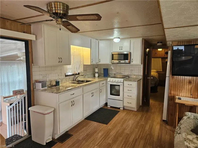 Kitchen featuring electric stove, stainless steel microwave, a ceiling fan, and light wood-style flooring
