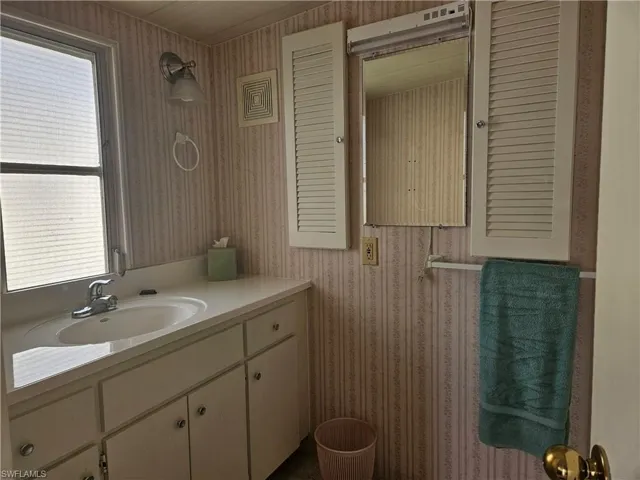 Bathroom featuring vanity, wallpapered walls, and plenty of natural light