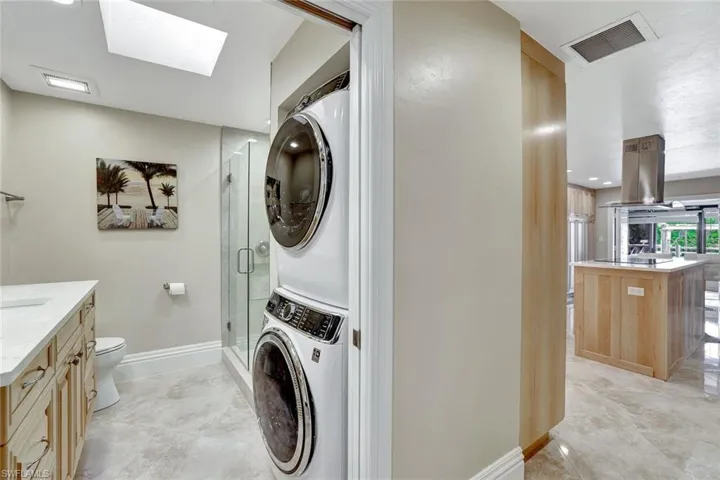 Laundry area featuring a skylight and stacked washer and clothes dryer