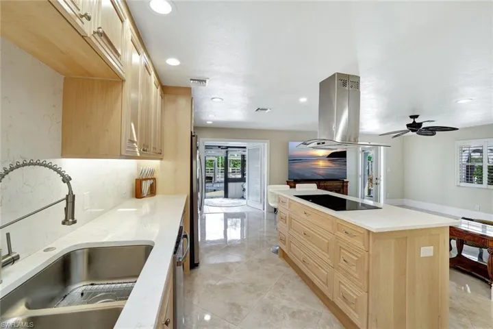 Kitchen with appliances with stainless steel finishes, light brown cabinetry, island exhaust hood, a center island, and sink