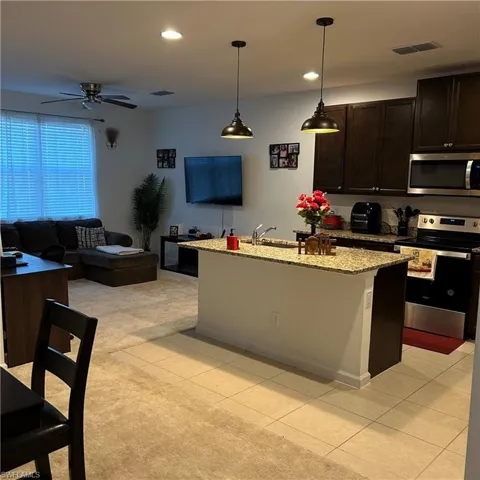 Kitchen featuring visible vents, light tile patterned flooring, ceiling fan, stainless steel appliances, and light colored carpet