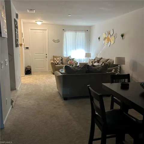 Living room with visible vents, light colored carpet, and baseboards