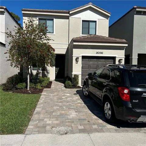 Traditional-style house with an attached garage, driveway, and stucco siding