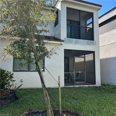 Back of property with a lawn, a sunroom, and stucco siding