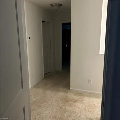 Corridor featuring carpet flooring and baseboards